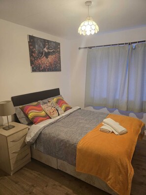 A bedroom with a bed, nightstand, lamp, and a painting on the wall. - Modern 2-Bed Apt Near Hospital and University of Birmingham (Birmingham)