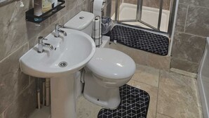 A bathroom with a shower, two sinks, a toilet, and a mirror. - Modern 2-Bed Apt Near Hospital and University of Birmingham (Birmingham)