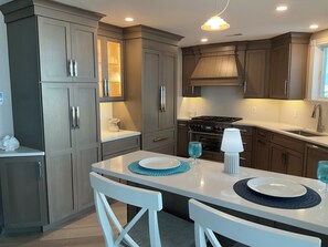 A modern kitchen with grey cabinets, a white countertop, and a gas stove. - Penthouse Apartment, Ocean View & Pool View, 4 BR, 3 Bath (Wildwood Crest)