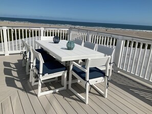 Eine weiße Terrasse mit Tisch und Stühlen mit Blick auf einen Strand.