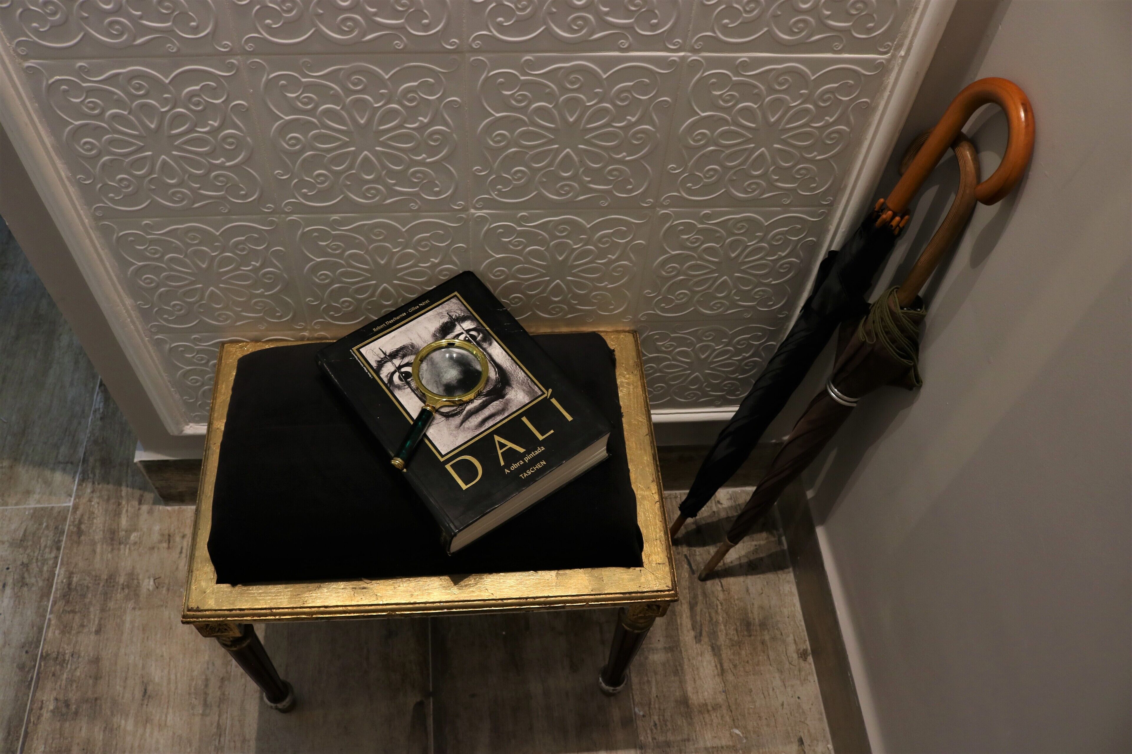 Une petite table sur laquelle se trouvent un livre intitulé « DALI » et une paire de chaussures.