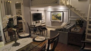 Ein Wohnzimmer mit Essbereich, einer Treppe und einem Flachbildfernseher.