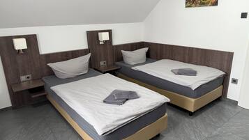 A room with two beds, a nightstand, a wall-mounted TV, and a small picture.