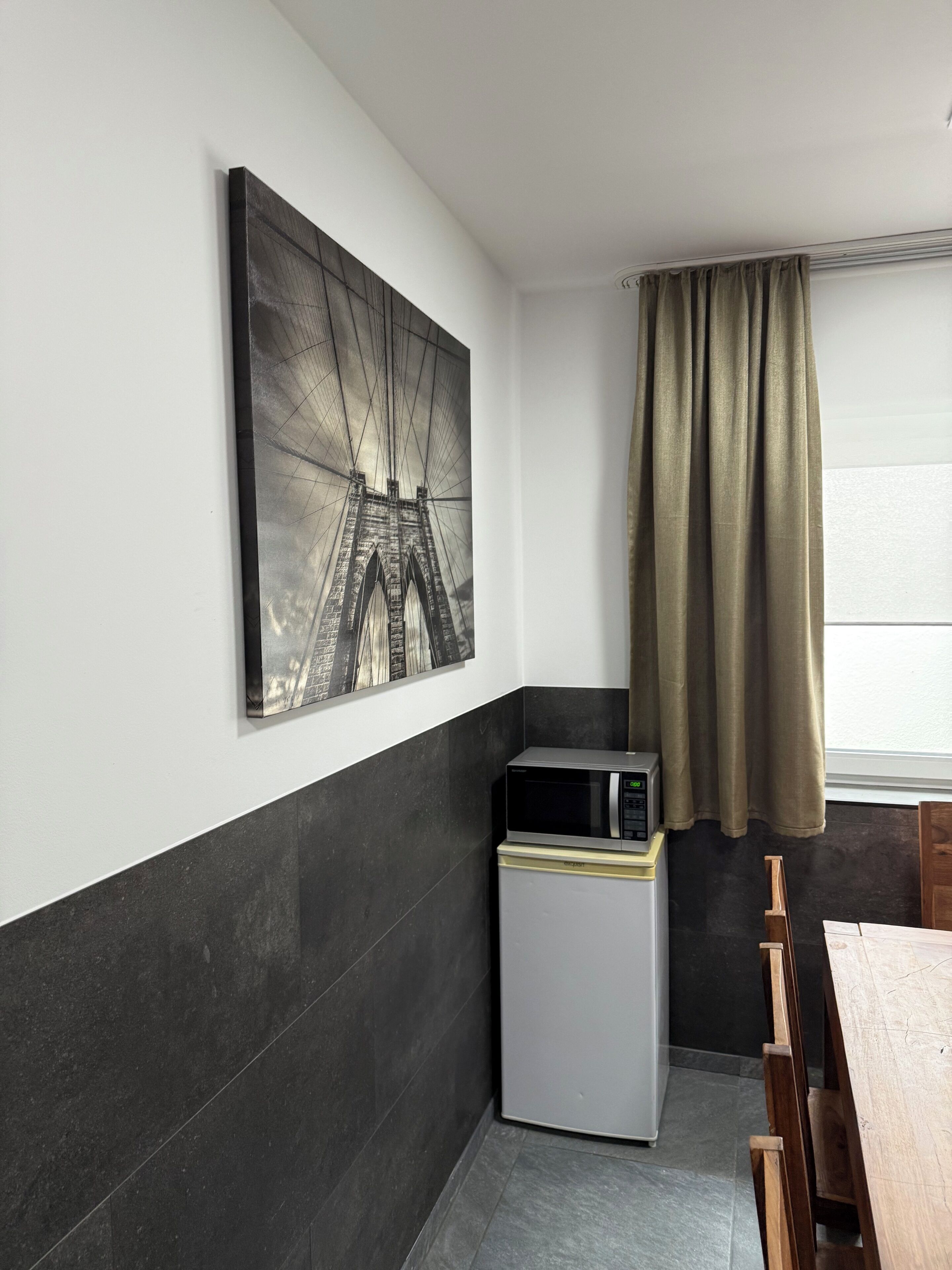 A compact kitchen with a microwave, a refrigerator, and a dining area with a table and chairs.