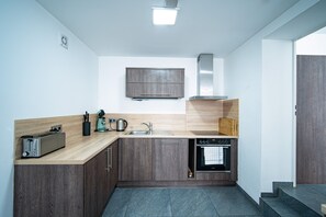 A modern kitchen with wooden cabinets, a built-in oven, a toaster, and a coffee maker. - Blauer Stein - Core it02- Haus (Bergheim)