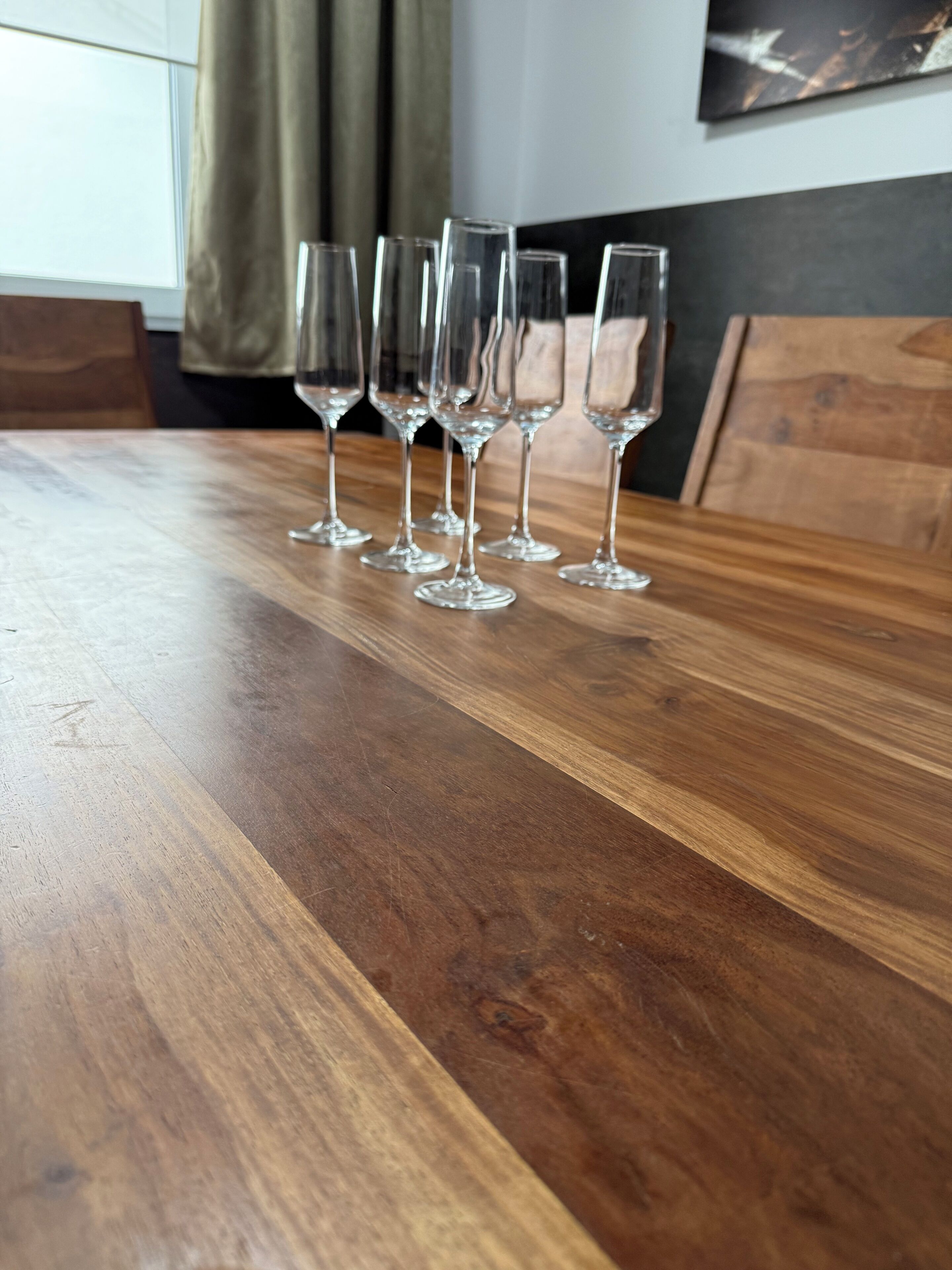 Una mesa de madera con seis copas de vino transparentes dispuestas sobre ella.