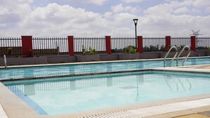 A swimming pool with a metal ladder, surrounded by a red and black fence, and a lamp post in the background. - 'THE TEAL' PREMIUM FURNISHED LUXURY 2-BEDROOM APARTMENT — MOVE-IN READY (Kenya)
