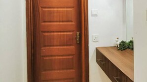 A wooden door with a handle, a white wall, and a wooden cabinet with a mirror above it.