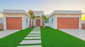 Een modern huis met twee verdiepingen, een centrale ingang, twee garages en een keurig onderhouden gazon.