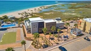 Een modern hotel met een zwembad, uitzicht op het strand en een parkeerplaats.