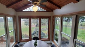 A room with a large window, a ceiling fan, and a table with chairs. - Amish View Manor - Hot tub w/ Large Outdoor Lot (Lancaster)