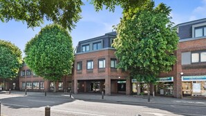 A street view with a row of brick buildings, including a pharmacy and a restaurant. - Central 2 Bed Flat, Free Parking, Gym, Cinema Room (Bedford)
