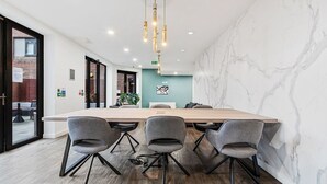 A conference room with a large table, four grey chairs, a hanging light fixture, and a marble wall. - Central 2 Bed Flat, Free Parking, Gym, Cinema Room (Bedford)