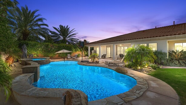 A swimming pool with a stone border, surrounded by a patio area with lounge chairs and a covered seating area. - Desert Luxe Oasis: Private Pool and 4+ BR in Gated South La Quinta! (La Quinta)