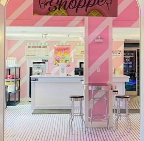 A shoppe with a pink and white color scheme, featuring a counter with a menu for soft serve cones and cups, and a security warning sign. - Ultimate Townhome-Pool/Lazy River-Waterslide-Hot Tub-Near Disney-No Resort Fees- (Davenport)