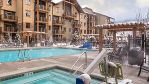 A hotel pool area with a clear blue pool, lounge chairs, and a covered seating area. - Spacious 3 bedroom in Magical Park city Utah (Park City)