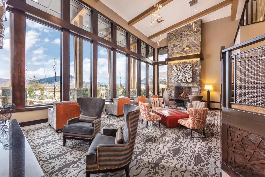 A spacious lounge with large windows, comfortable seating, and a stone fireplace.