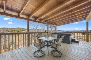 Um terraço ao ar livre com pérgola de madeira, uma mesa com cadeiras e uma churrasqueira.
