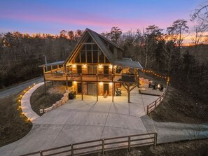 Un grand chalet à deux étages, doté d’une véranda qui fait le tour du bâtiment et de fondations en pierre.