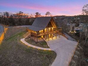 Uma pousada moderna com telhado inclinado, um deck coberto e uma entrada com calçada.
