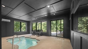 A modern indoor pool area with a clear view of the surrounding greenery through large windows. - On The Rocks|Luxury Mtn Cabin w/ Indoor Pool (Sevierville)