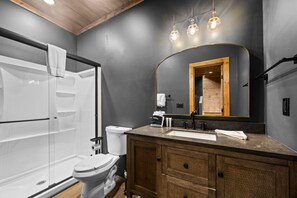 Une salle de bain moderne dotée d’une douche à l’italienne, de toilettes et d’un meuble-lavabo avec un miroir.