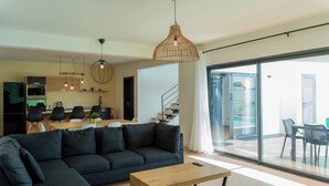 A modern living room with a dark sofa, a wooden coffee table, and a dining area with a table and chairs. - Villa Aaya Grand Baie, Private Pool,3 Bedrooms, 7 mins to Pereybere beach (Moka District)