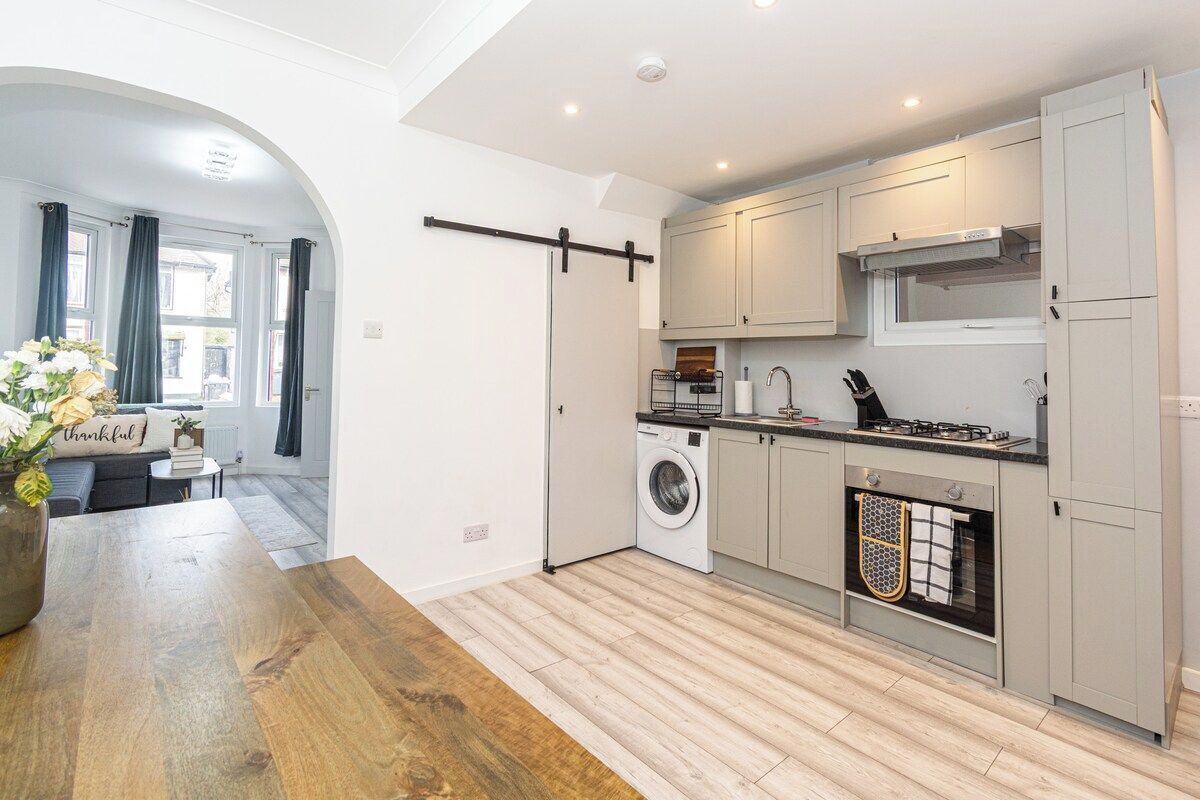 A modern kitchen with a washing machine, a gas stove, and a built-in oven.