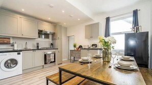 A modern kitchen with a wooden dining table, built-in appliances, and a view of the outdoors.