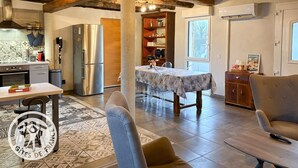 A spacious living area with a dining table, a sofa, and a kitchen with modern appliances. - Gîtes de France® - Héloïse's gîte (BETAILLE)