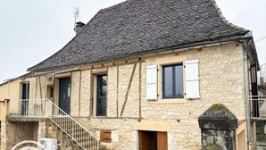 A stone building with a steep roof, a small porch with a white railing, and a wooden door. - Gîtes de France® - Héloïse's gîte (BETAILLE)