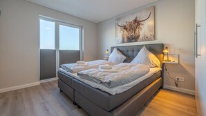 Camera moderna con un letto grande, una finestra e un'opera d'arte appesa al muro raffigurante un toro.