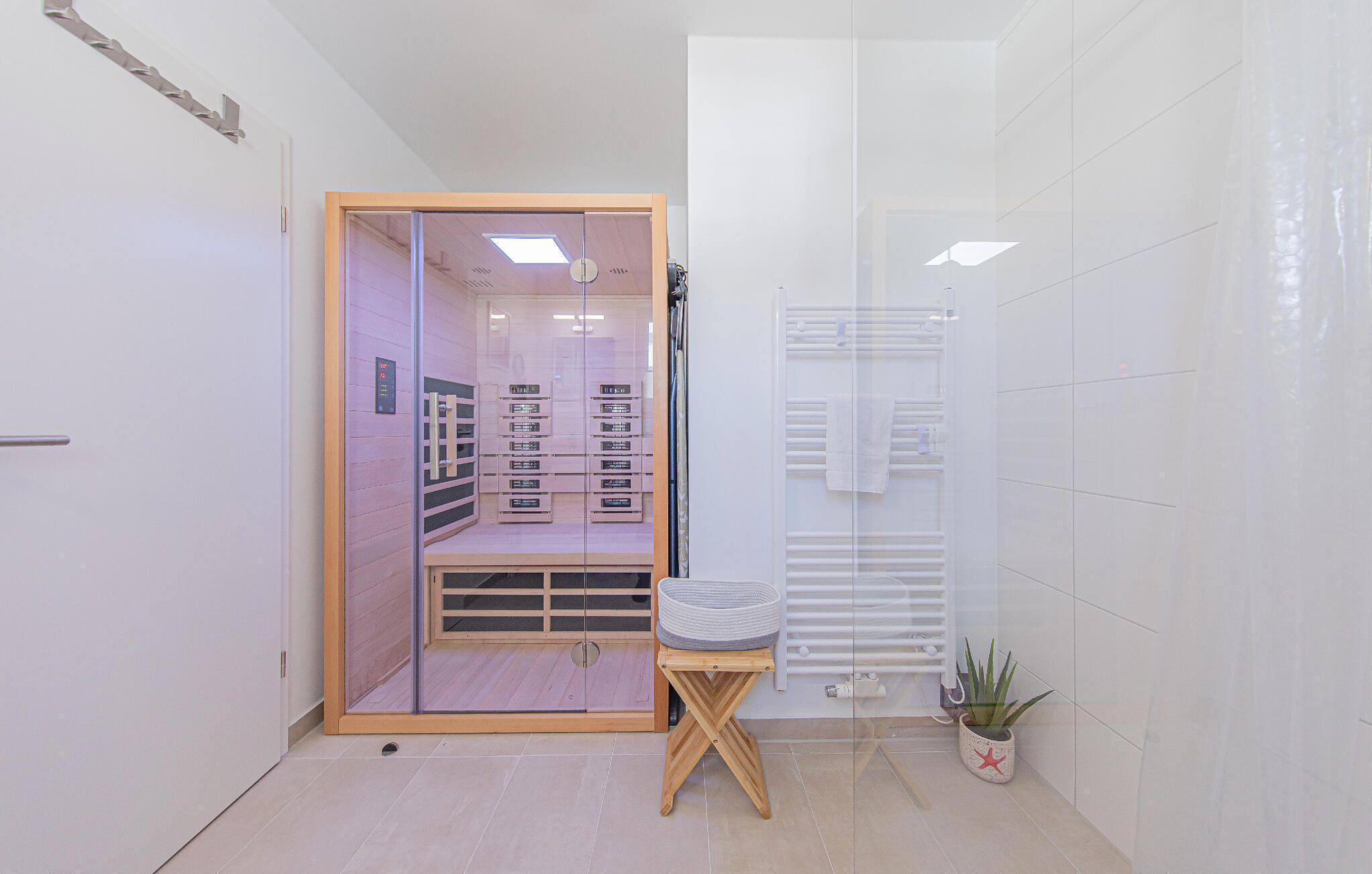 A modern bathroom with a glass shower enclosure, a wooden vanity, and a potted plant.