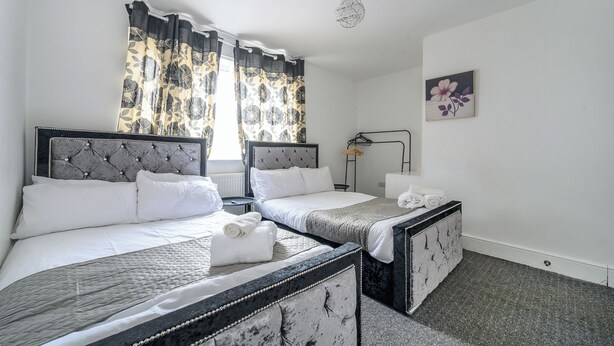 Een hotelkamer met twee bedden, een nachtkastje, een lamp en een schilderij aan de muur.