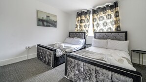 Een tweepersoonsbed met een marmeren hoofdbord, een kleiner bed met een vergelijkbaar hoofdbord, en een schilderij van een brug aan de muur.