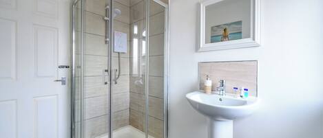 A modern bathroom with a glass-enclosed shower, a white sink, and a framed picture on the wall.