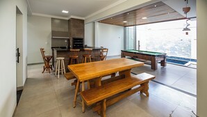 A spacious room with a wooden dining table, bar stools, and a pool table.