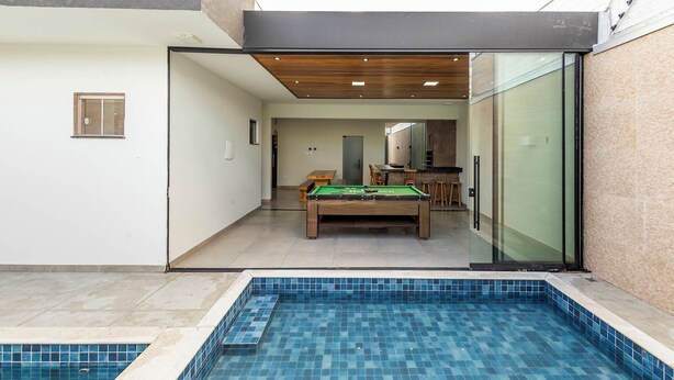 A modern indoor pool area with a pool table and a dining area.