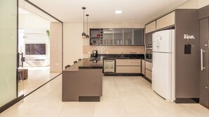A modern kitchen with a central island, a built-in oven, and a refrigerator.