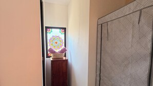 Un pasillo estrecho con un armario de madera, una cortina estampada y un ventanal decorativo con un diseño colorido.