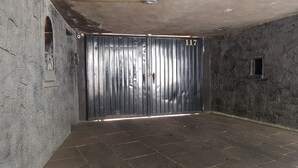 Una habitación con una puerta metálica grande, paredes de piedra y suelo de baldosas.