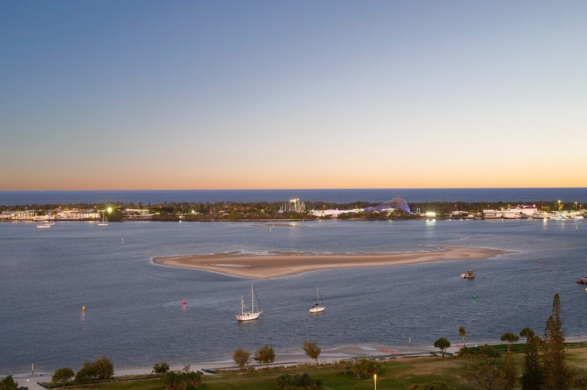 A coastal view with boats, a sandy beach, and a distant amusement park.