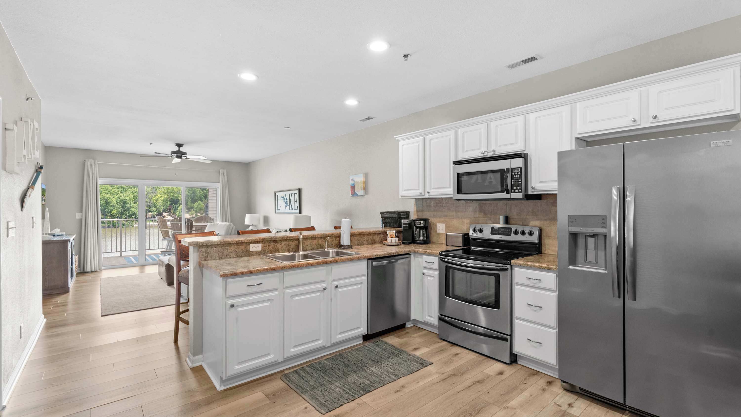 A modern kitchen with white cabinets, stainless steel appliances, and a large island with a sink.