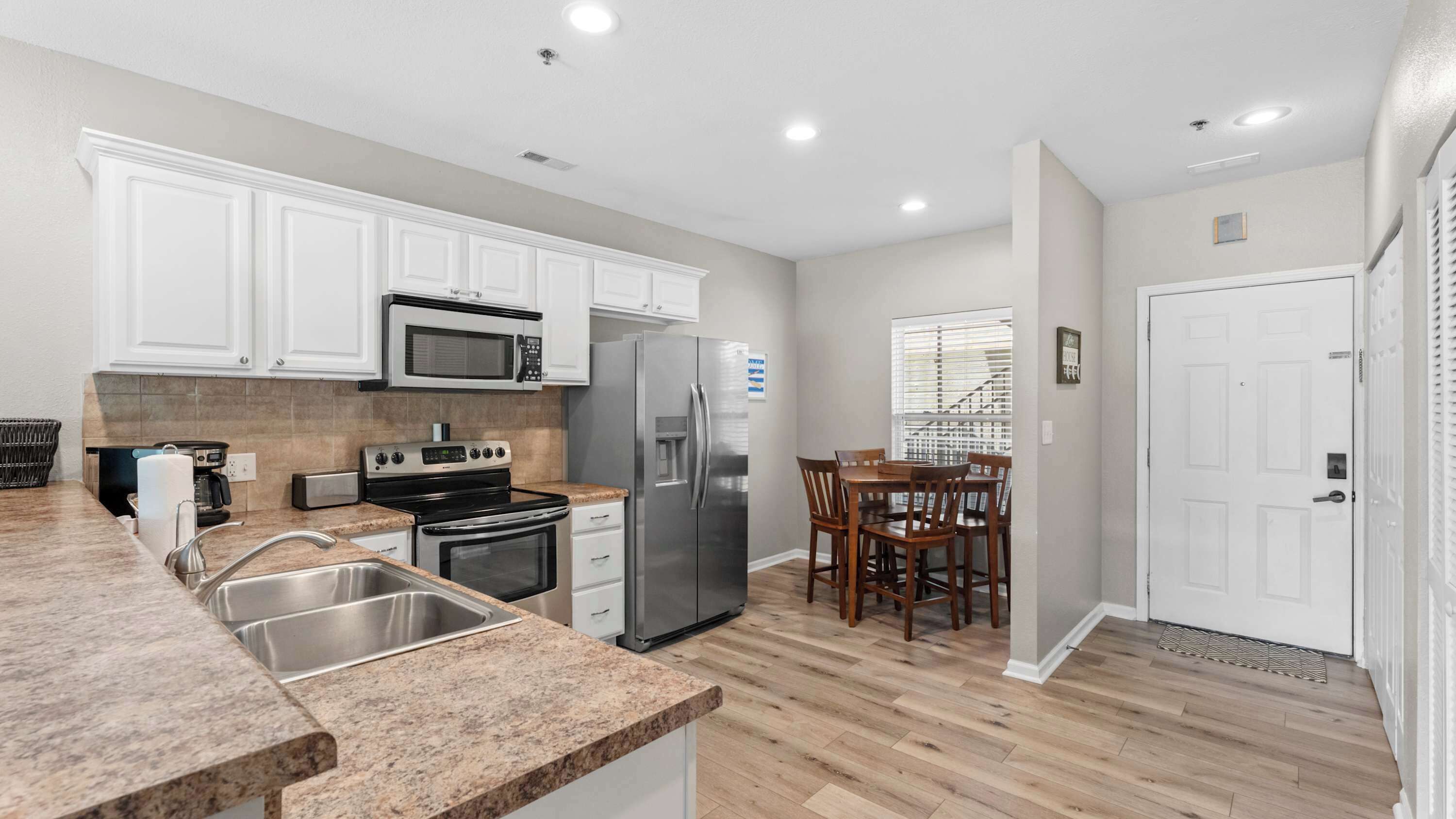 A modern kitchen with white cabinets, stainless steel appliances, and a granite countertop.