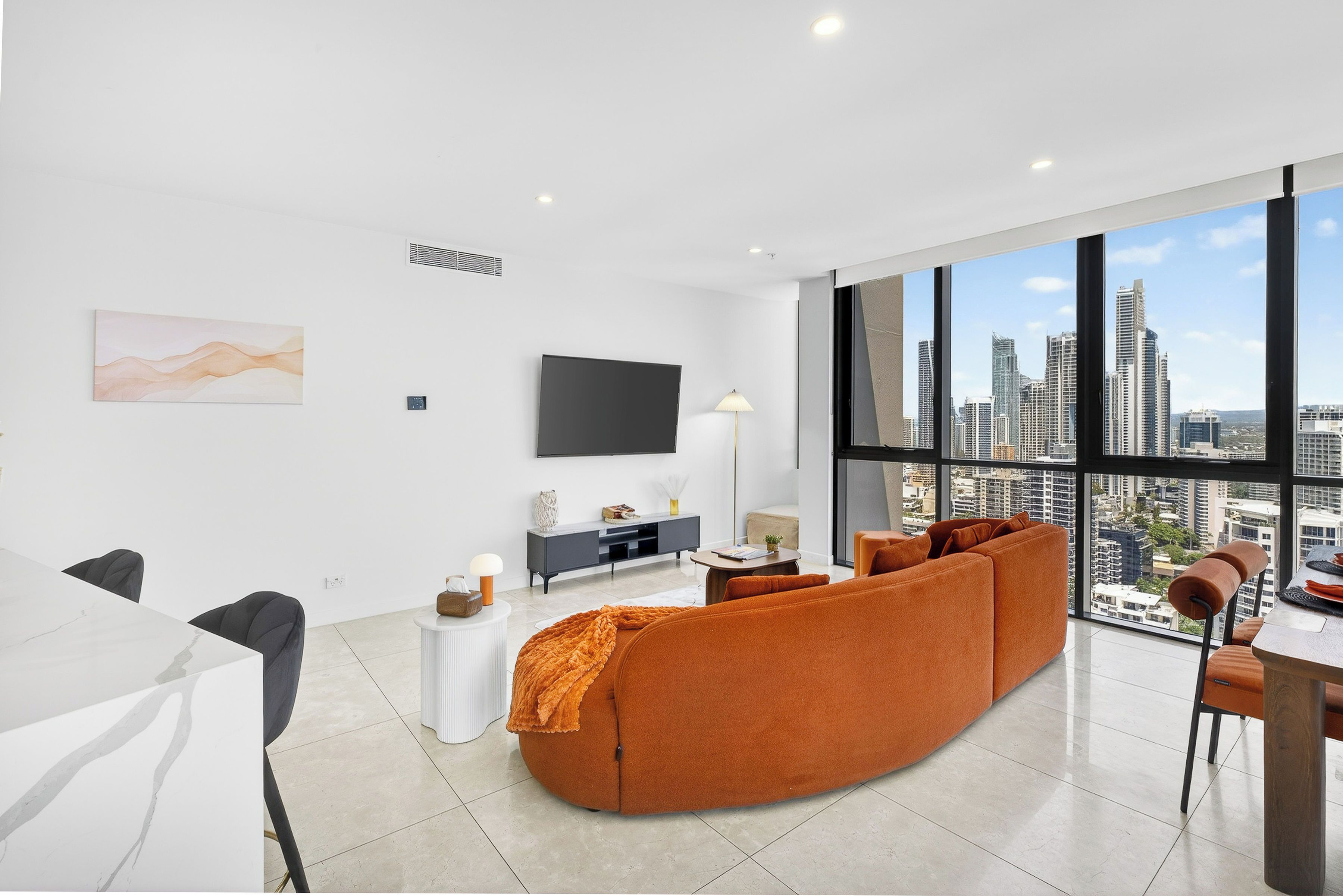 A modern living room with a large window, a flat-screen TV, and a sofa.