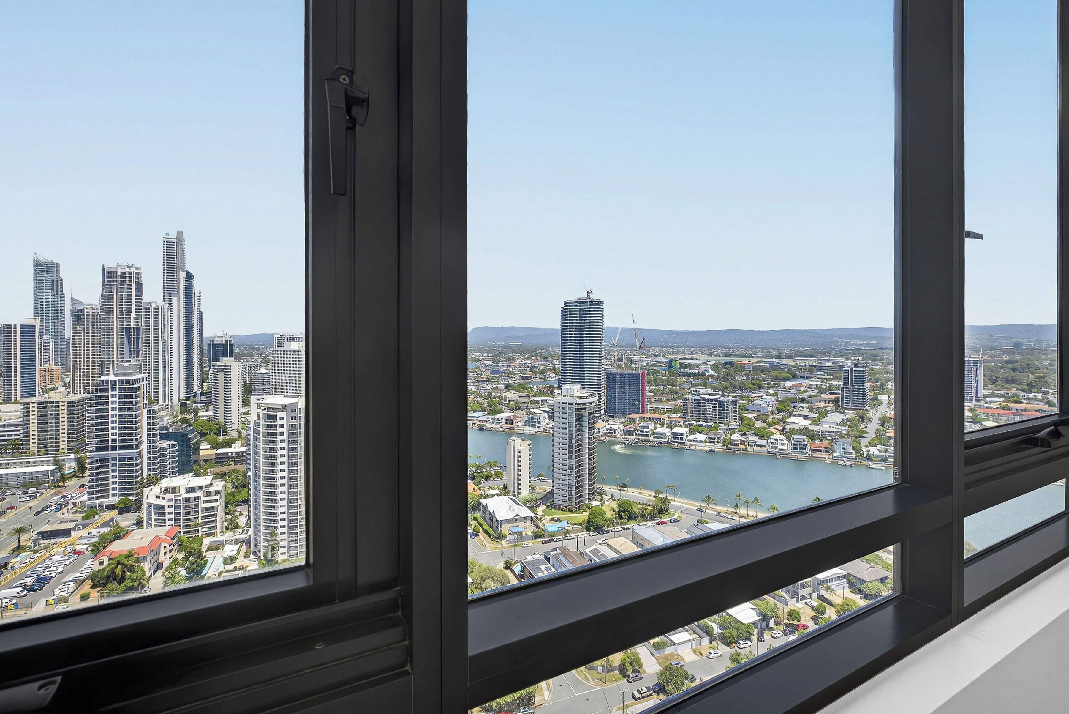 A high-rise building with a view of a cityscape and a river.