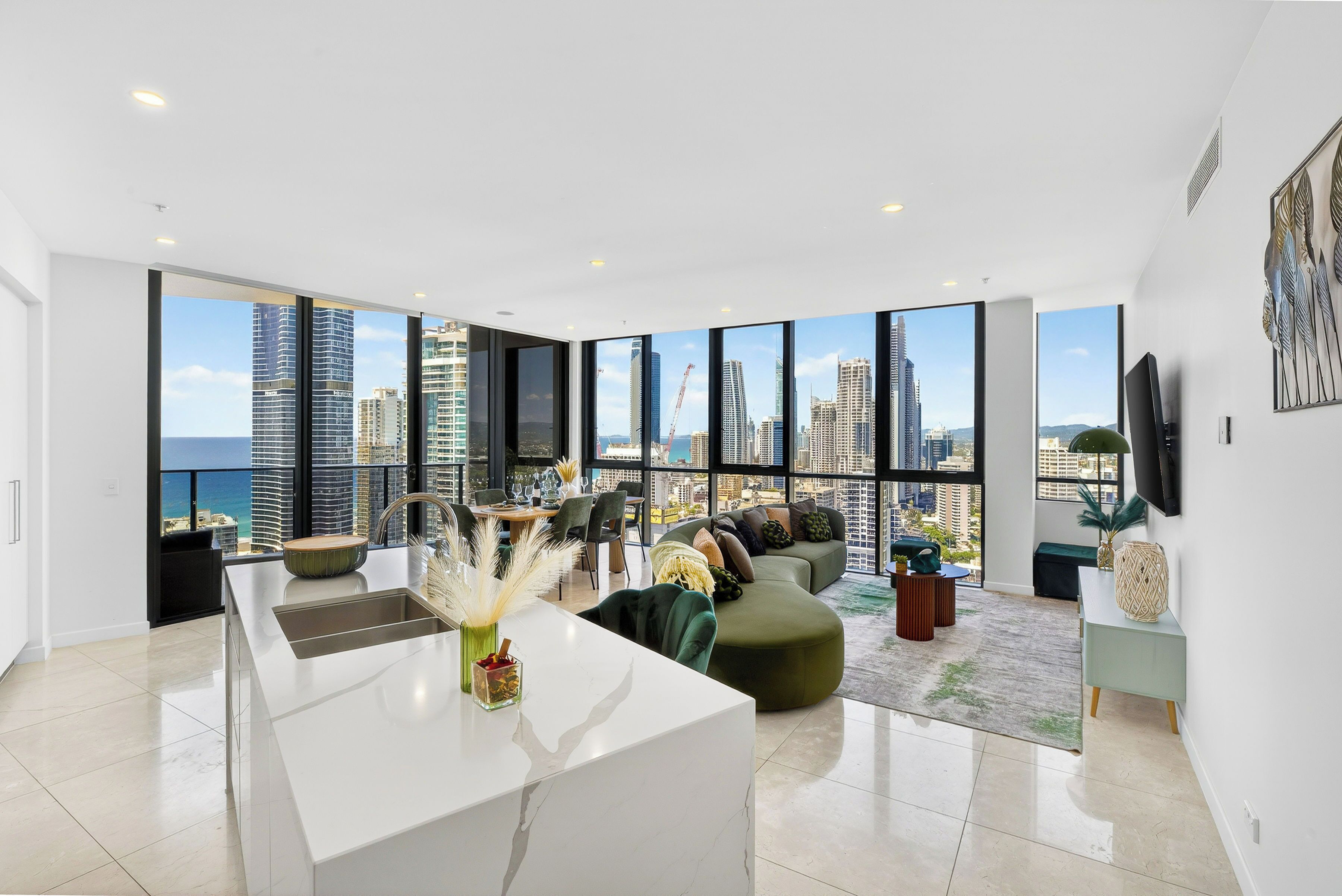 A modern living room with a large window, a kitchen island, and a seating area with a view of the city skyline.