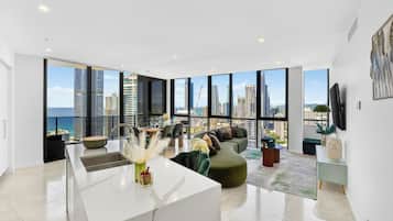 A modern living room with a large window, a kitchen island, and a seating area with a view of the city skyline.