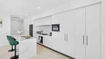 A modern kitchen with white cabinetry, a built-in microwave, and a central island with bar stools.