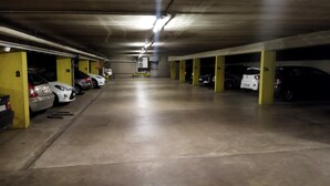 An underground parking garage with multiple parking spaces, concrete floors, and yellow pillars. - Two bedrooms apartment with free underground parking place (Etterbeek)